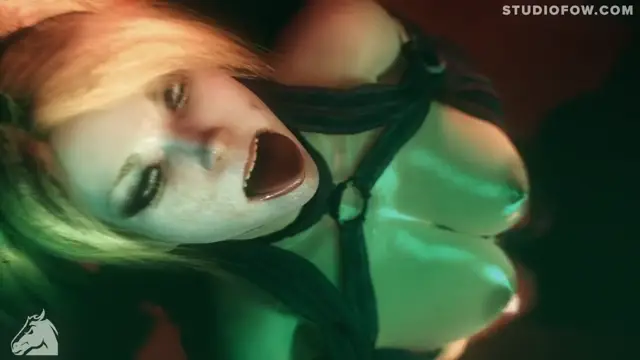 A close-up shot shows a blonde woman with a shocked expression and open mouth, wearing a black harness over her large breasts, with a green light illuminating her skin. Screenshot from Agent Of Chaos