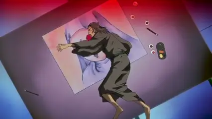 An anime man in a kimono is lying face-down on a table next to a large painting of a woman's torso, surrounded by several small objects including a remote control. Screenshot from Hana Dorei - Episode 2