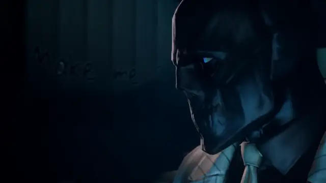 A close-up shot of a man wearing a dark, metallic-looking mask with glowing blue eyes and a suit, looking downward next to a wall with the words "Make me" written on it. Screenshot from Scarlet Nights