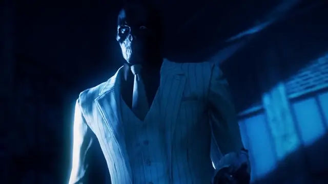 A man with a skull-like mask wearing a pinstriped suit stands in a dimly lit, blue-toned room. Screenshot from Scarlet Nights