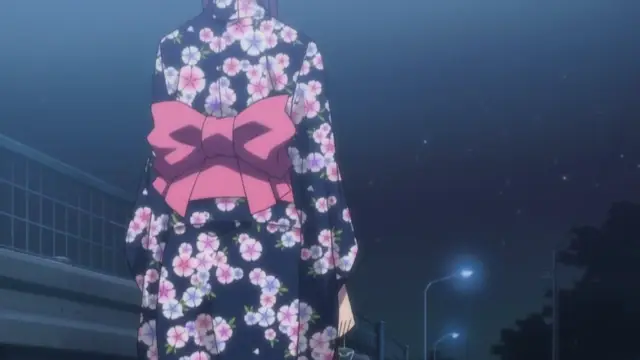 A girl in a dark blue kimono with a pink floral pattern and a large pink bow stands outside at night. Screenshot from Nee Summer! - Episode 2