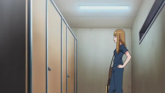 A woman with long blonde hair wearing a blue jumpsuit stands in a locker room, looking towards a row of lockers on the left. Screenshot from Nee Summer! - Episode 2