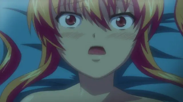 A close-up shot of an anime girl with pink and yellow hair, wide eyes, and a blushing face as she lies on a blue bed with a shocked expression. Screenshot from Inshitsu Otaku ni Ikareru Kanojo - Episode 3