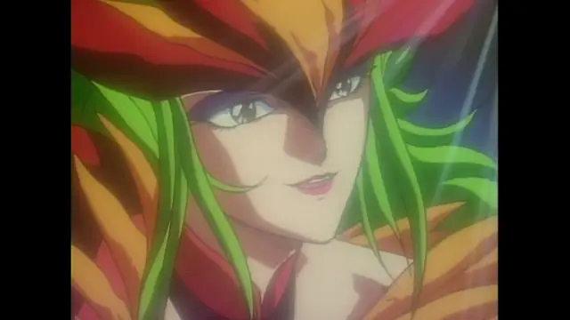 A close-up of an anime character with long green hair and a red and orange headdress smiling mischievously at the camera. Screenshot from Imma Youjo: The Erotic Temptress - Episode 5