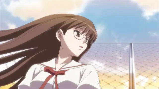 An anime girl with long brown hair and glasses, wearing a white and red sailor uniform, stands in front of a chain-link fence under a bright sunny sky. Screenshot from Aki Sora: In a Dream - Episode 2
