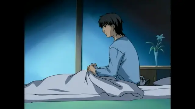 A pensive young man with black hair sits on a bed, wrapped in a blanket and looking out of a window at the night sky. Screenshot from Slave Nurses - Episode 1