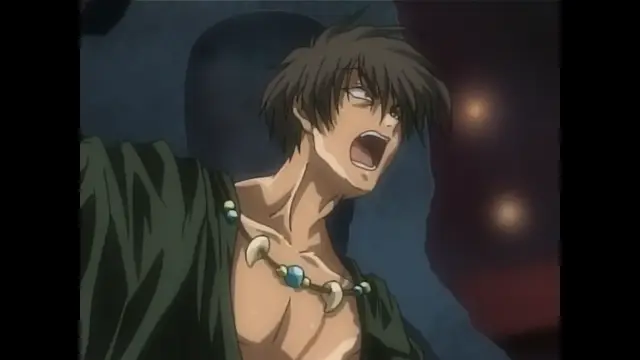 A muscular anime man with brown hair, wearing an open green robe and a necklace of large teeth and blue gems, screams with an intense expression while being held against a blue stone structure. Screenshot from Moonlight Lady - Episode 5