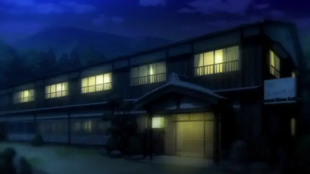 A two-story traditional Japanese inn (ryokan) glows with warm yellow light from its windows at night, situated against a backdrop of dark mountains and a moonlit sky. Screenshot from Aku no Onna Kanbu Full Moon Night R - Episode 2