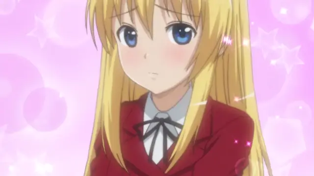 An anime girl with long blonde hair and blue eyes wears a red school uniform and looks on with a blushing, slightly dazed expression against a pink background filled with hearts and sparkles. Screenshot from Koiito Kinenbi - Episode 1