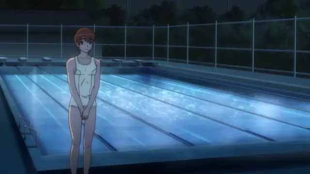 A young woman with short orange hair wearing a white swimsuit stands at the edge of an outdoor swimming pool at night. Screenshot from Tsundere Inran Shoujo Sukumi - Episode 2
