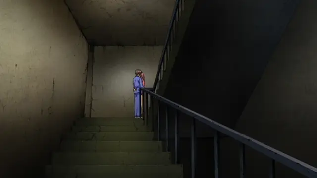 A girl in a blue school uniform stands at the top of a concrete staircase in a dark, dimly lit hallway. Screenshot from Grope: Yami no naka no Kotoritachi - Episode 1