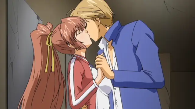 A blonde man in a blue suit leans in to kiss a brown-haired girl in a red and white tracksuit against a gray wall. Screenshot from Grope: Yami no naka no Kotoritachi - Episode 1