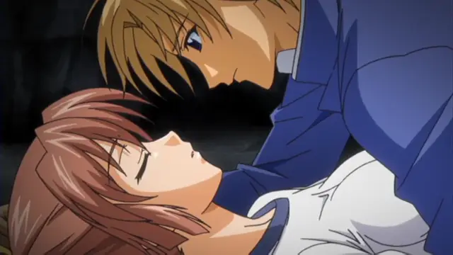 A blond man in a blue shirt leans over a brown-haired woman who is lying down, his face close to hers as if about to kiss her. Screenshot from Grope: Yami no naka no Kotoritachi - Episode 2