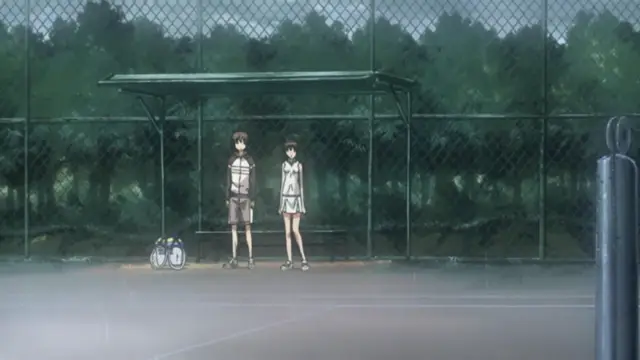 In a rainy outdoor sports court, a male student in a school uniform and a female student in a sports dress stand together in front of a bench under a shed, with gym bags on the ground next to them. Screenshot from Fault!! - Episode 1