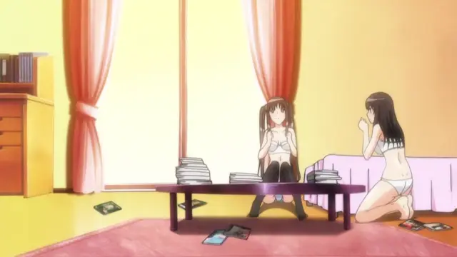 Two anime girls sit in a room, with one girl on a chair behind a table and the other kneeling on a rug, surrounded by stacks of books and cards. Screenshot from Fault!! - Episode 3