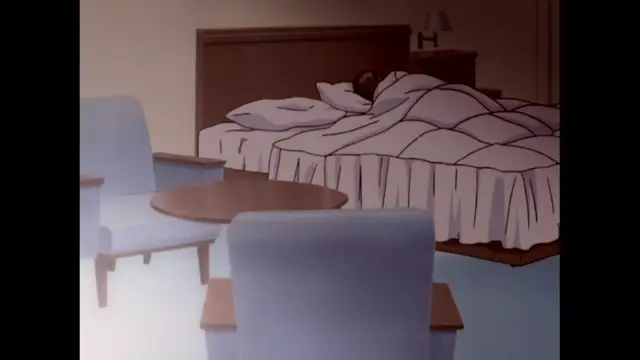 A person lies in a bed under a white comforter in a hotel room with a small table and chairs. Screenshot from The Immorals - Episode 1