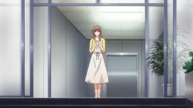 An anime girl with brown hair, wearing a yellow cardigan and a white apron, stands with her hands clasped together in a hallway. Screenshot from Eternity: Shin`ya no Nurekoi Channel - Episode 1
