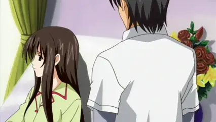 A long-haired woman in a light green and red dress sits on a bed facing a man with black hair wearing a white shirt and gray pants, while a bouquet of red and yellow flowers sits on a nearby table. Screenshot from Futari no Aniyome - Episode 2